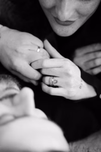 Black-and-white close-up of a couple holding hands, showing their rings