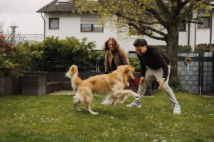 Couple playing with a golden retriever in a garden