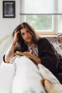 Woman reclining on a couch, reading a book with her hand resting on her head