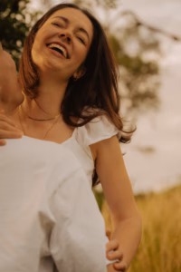Laughing woman with her hand on her partner's shoulder, standing in a field