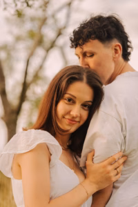 Close-up of a woman leaning against her partner outdoors, soft golden light