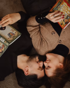 Overhead shot of a couple lying down forehead to forehead, each holding a book