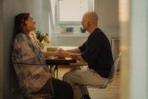 Couple holding hands at a small table by a sunlit window
