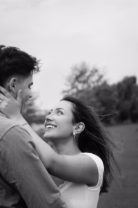 Black-and-white portrait of a couple embracing face to face outdoors, windswept hair