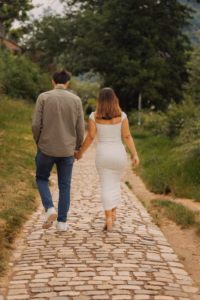 Couple walking hand in hand along a cobblestone path, seen from behind