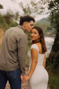 Man kissing his partner's forehead by the Neckar riverside, holding hands