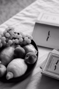 Black-and-white still life of a bowl of fruit and books on a linen tablecloth